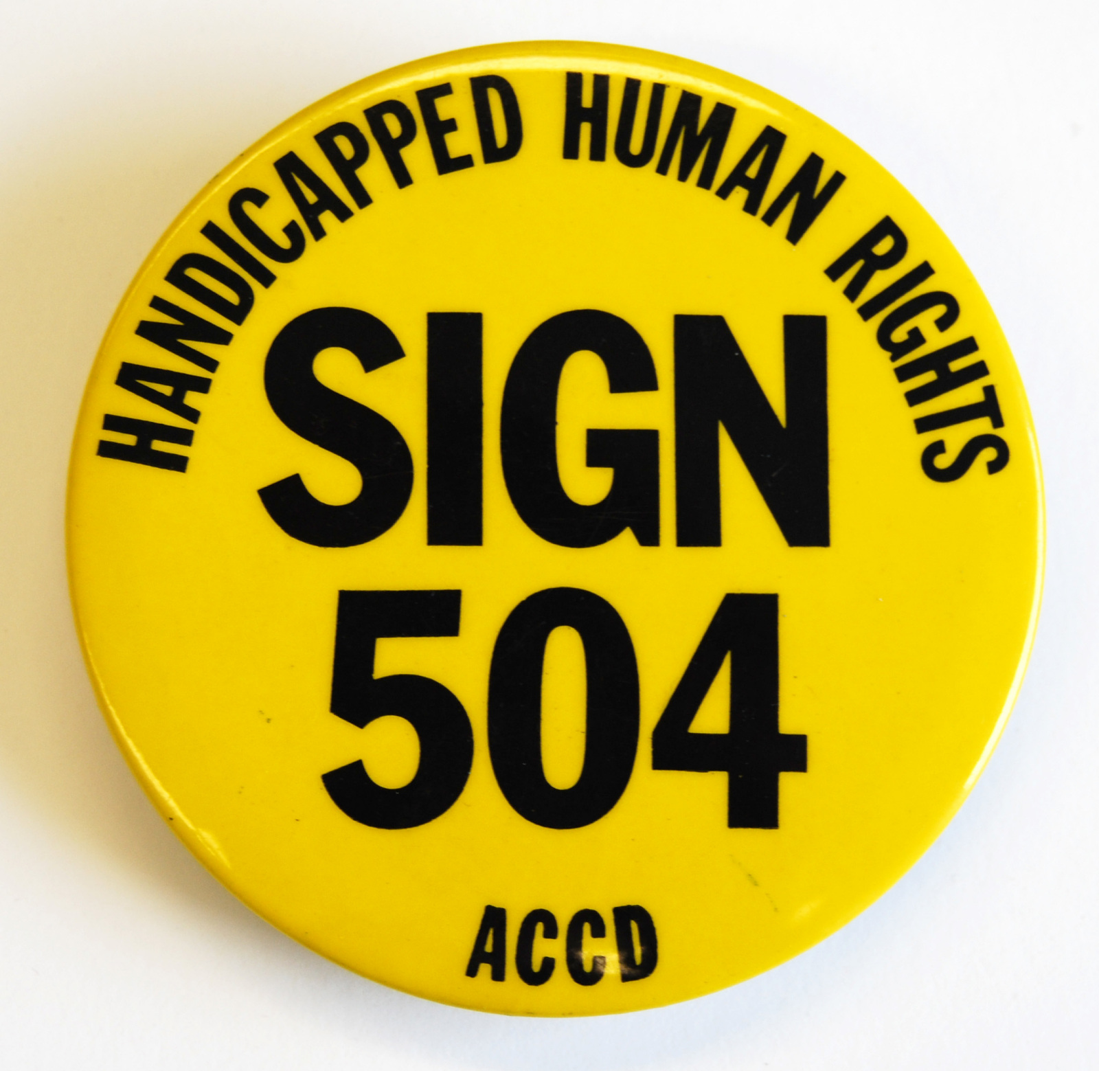 Round yellow button that reads "Handicapped Human Rights. Sign 504. ACCD"