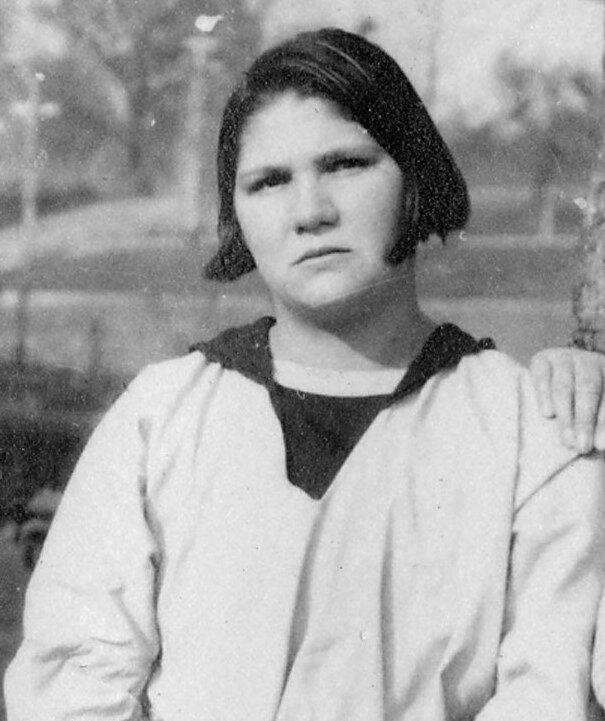 Carrie Buck with light skin, dark hair cropped at the chin and a white sailor-style top.