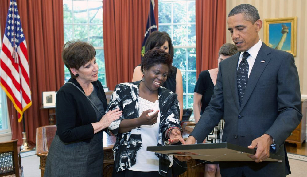 Lois Curtis shows president Obama a painting she made while Obama stands next to her holding the painting.