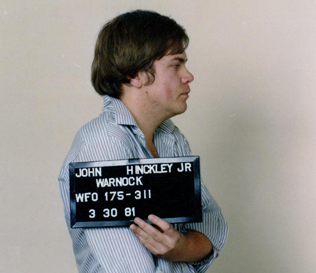 John Hinckley, Jr. holding identifying sign in his 1981 mugshot,