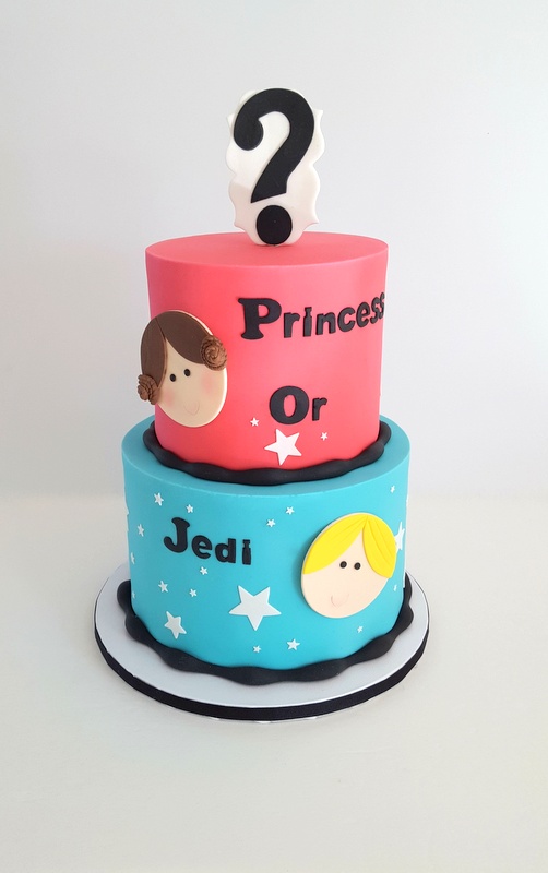 A tall two-tiered cake presumably for a gender reveal party. The top layer is pink with a cartoonish child's face (with blush and pigtails) in fondant and the words, "Princess or." The bottom layer is blue with a cartoonish child's face in fondant and the word, "Jedi." There is a large question mark on the top of the cake bringing the entire message to, "Princess or Jedi?"