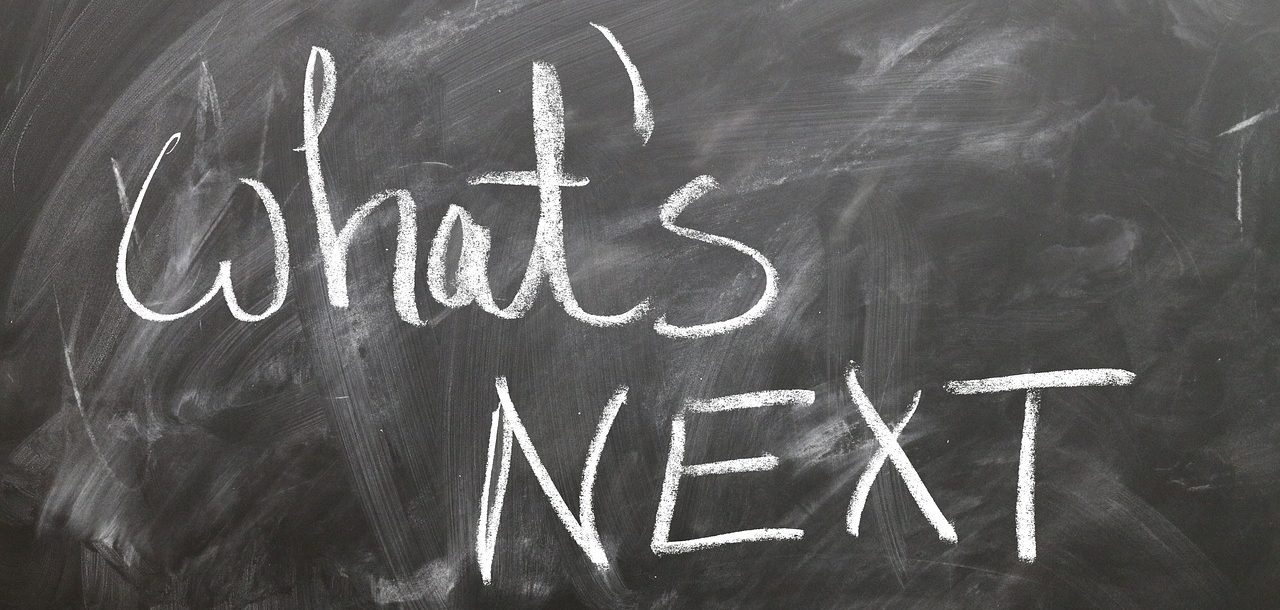 On a black chalkboard where many words have been erased, "what's next" is written in bold letters