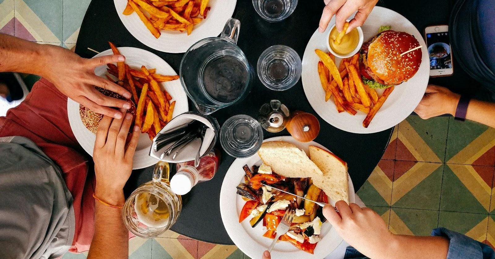 Four people with individual plates of food eat together at a restaurant.