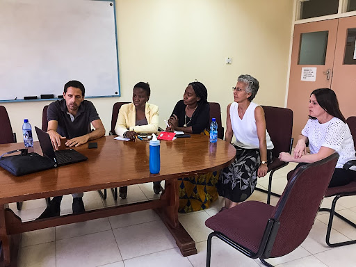 A racially diverse group gathered around a laptop discussing a client.