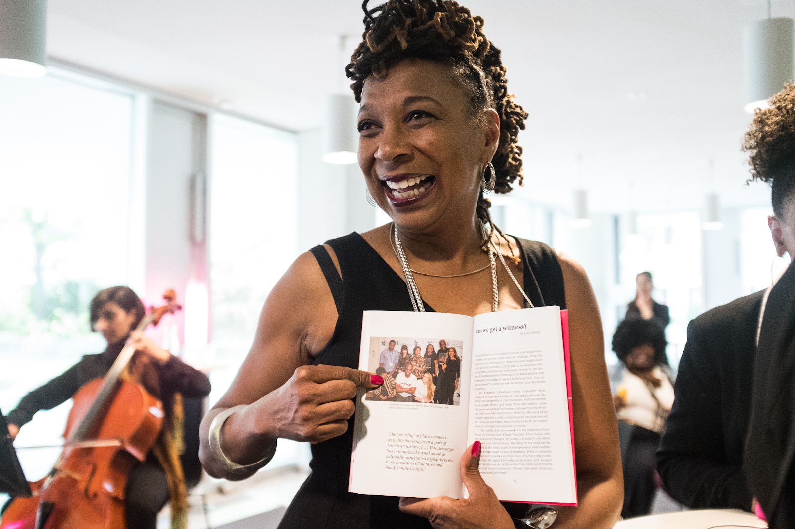 Kimberle Crenshaw smiling and pointing to a picture in a book.