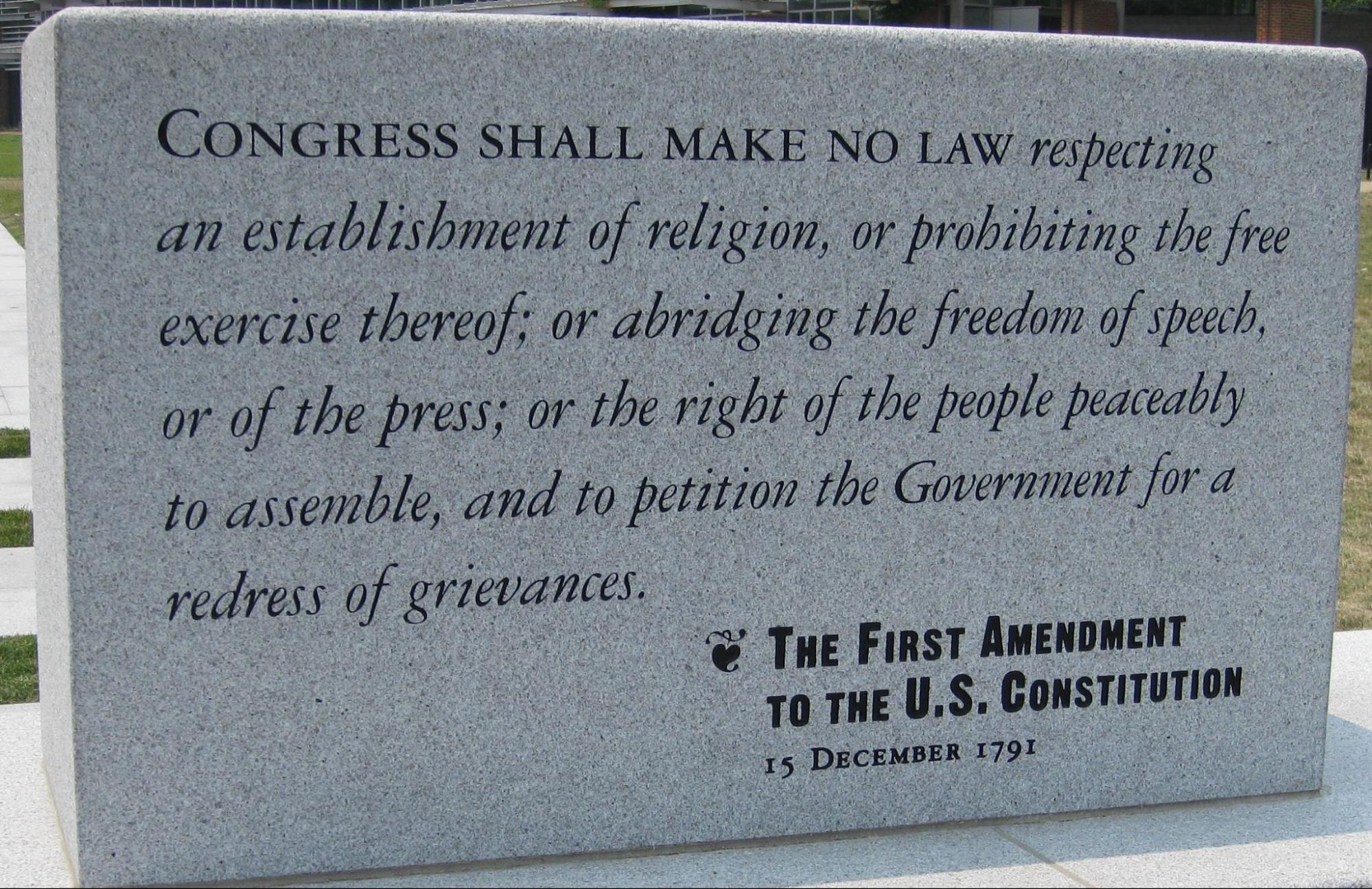 Photo of a stone inscribed: Congress shall make no law respecting an establishment of religion, or prohibiting the free exercise thereof; or abridging the freedom of speech, or of the press; or the right of the people peacably to assemble, and to petition the Government for a redress of grievances. The First Amendment to the US Constitution, 15 December 1791.