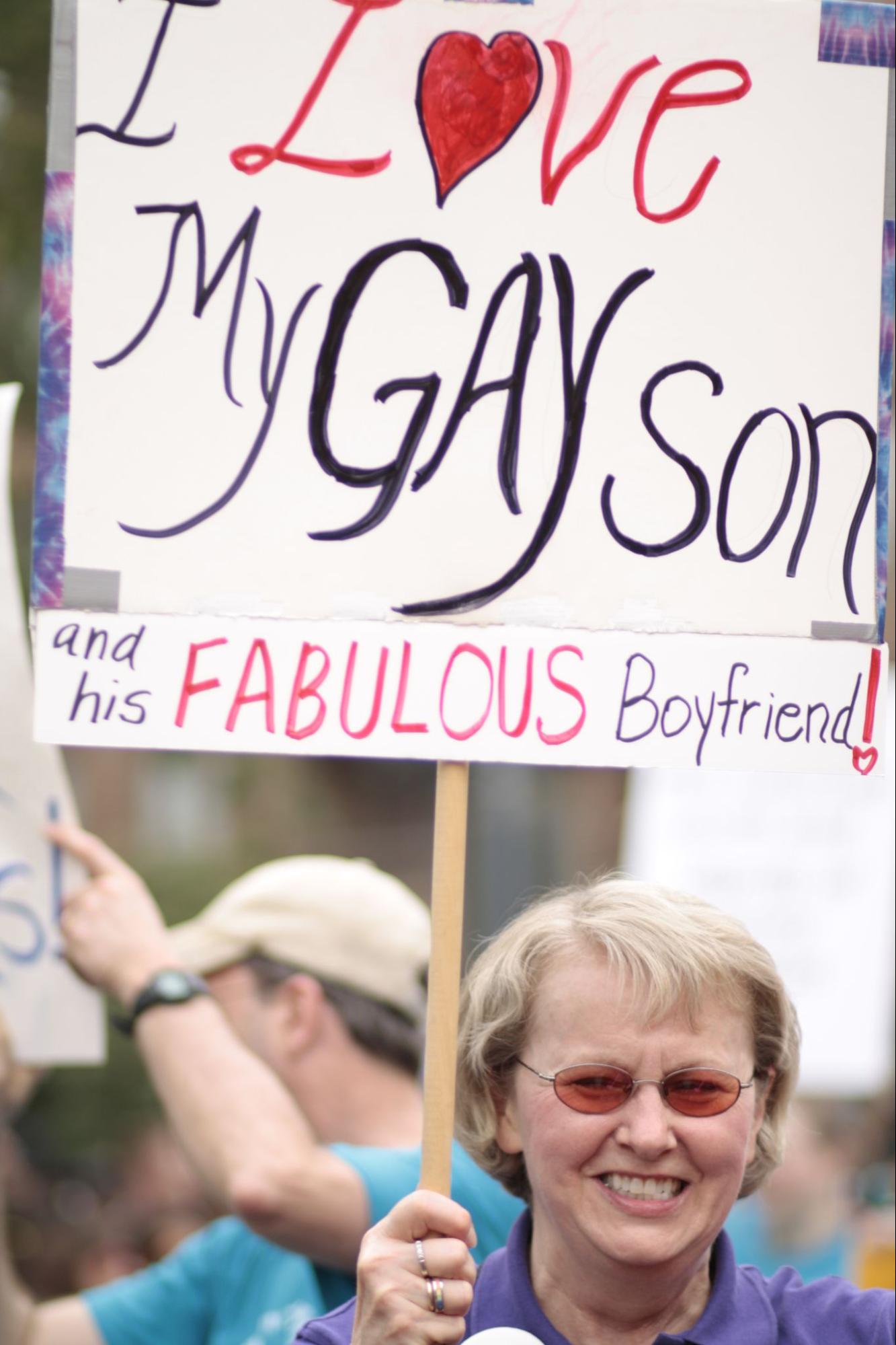 A protester holds a sign that says "I love my gay son and his fabulous boyfriend!"