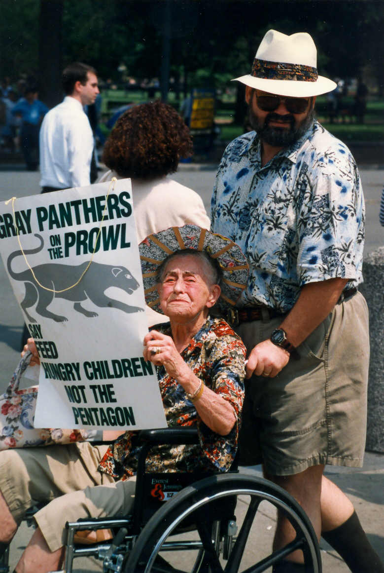 An older person in a wheelchair carries a sign that says "Gray panthers on the prowl say feed hungry children not the pentagon"