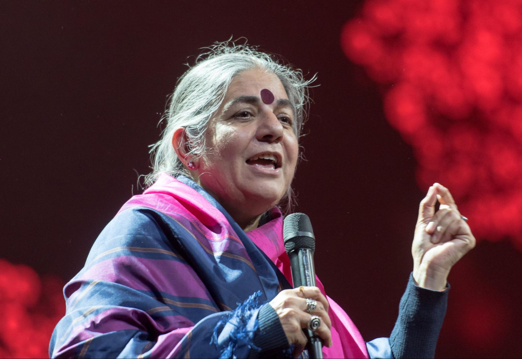 photo of a grey haired woman and a bindi, speaking with a microphone