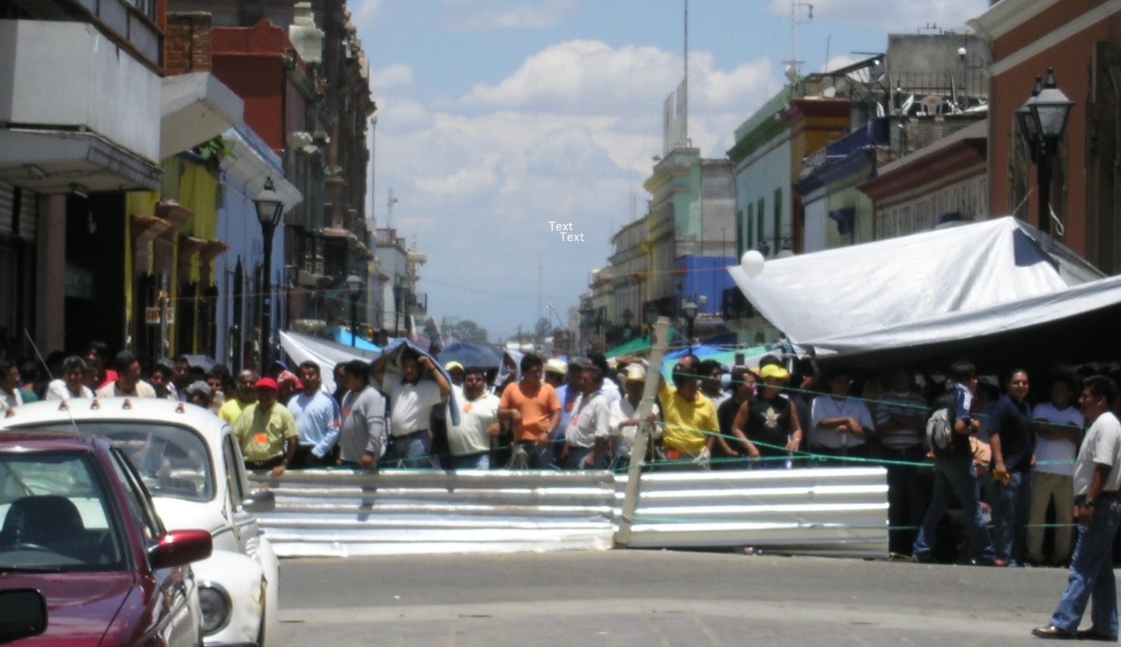 many protestors stand in the middle of a street with a metal barrier in front of them.