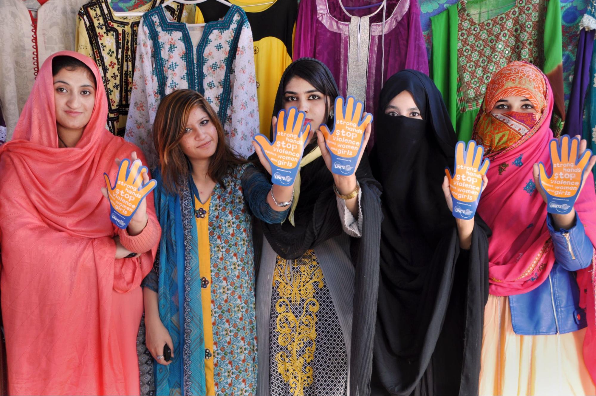 Five women, with garments covering their heads and faces to varying degree. Each are holding their hands up
