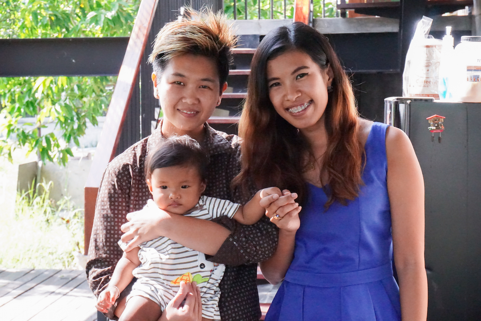 Two women stand beside each other, smiling, one holding a baby.