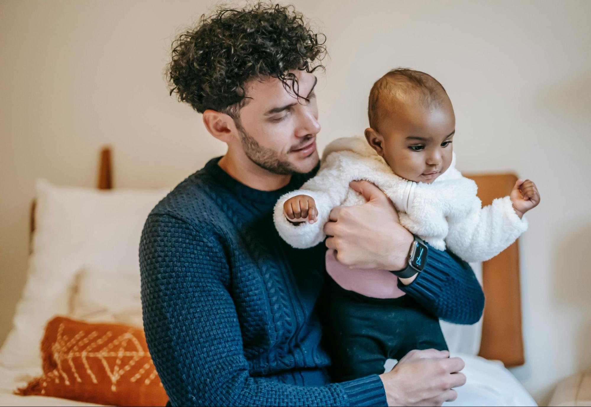 White father holds a baby of color