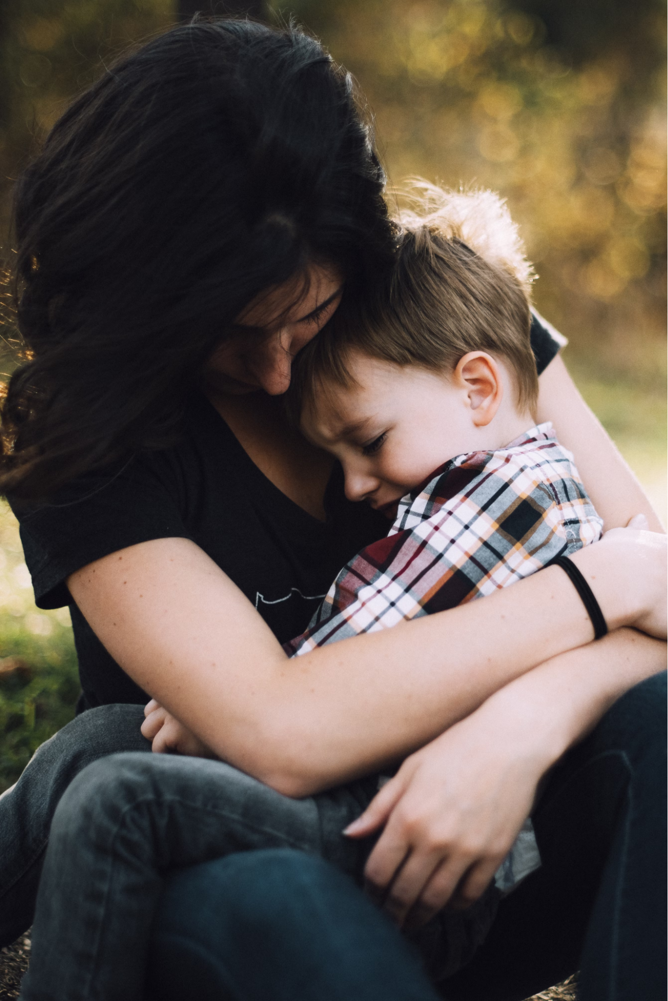 A female holds a make toddler closely who appears to be in distress.