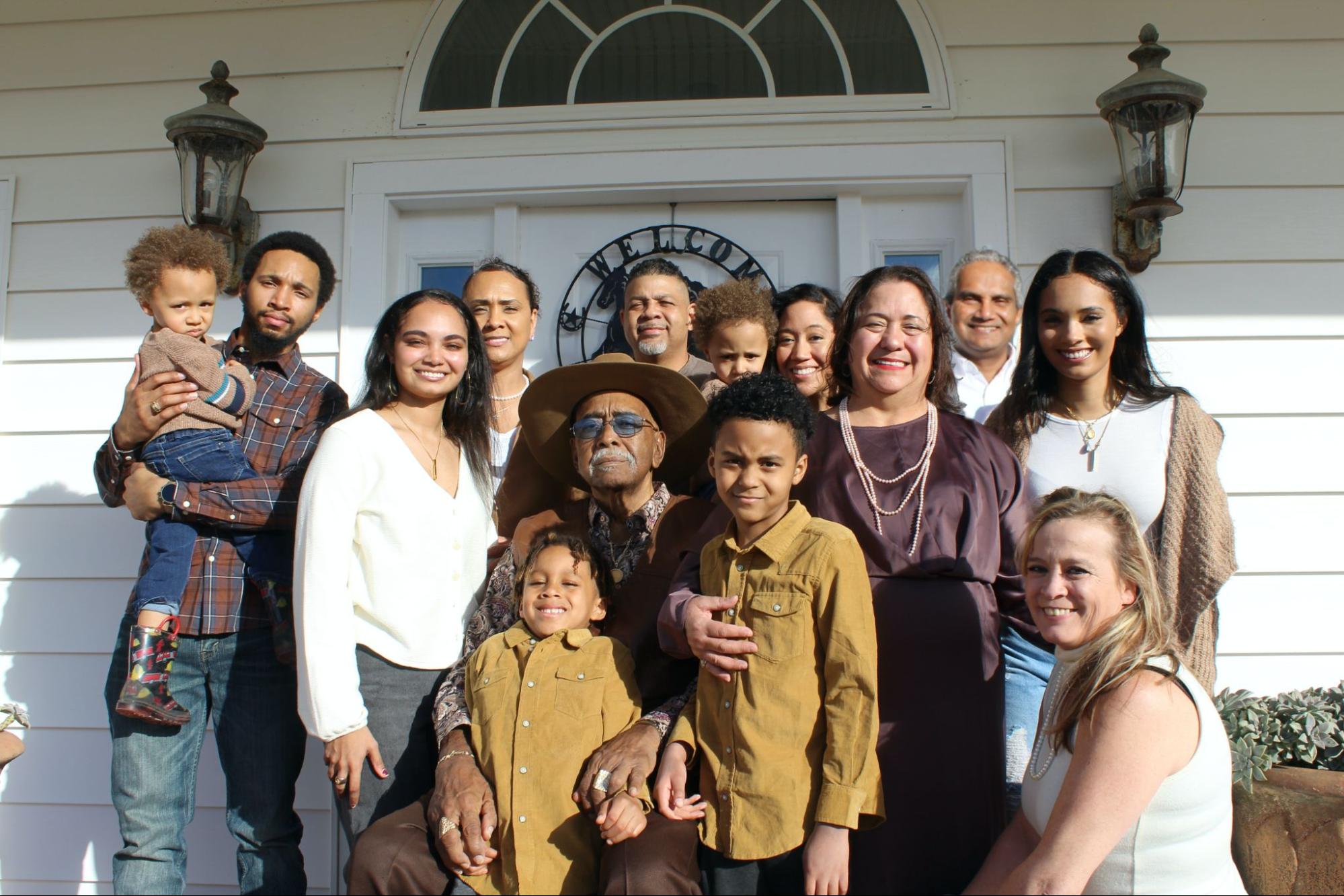 A multi-generational family with various skin tones poses for a group photo.