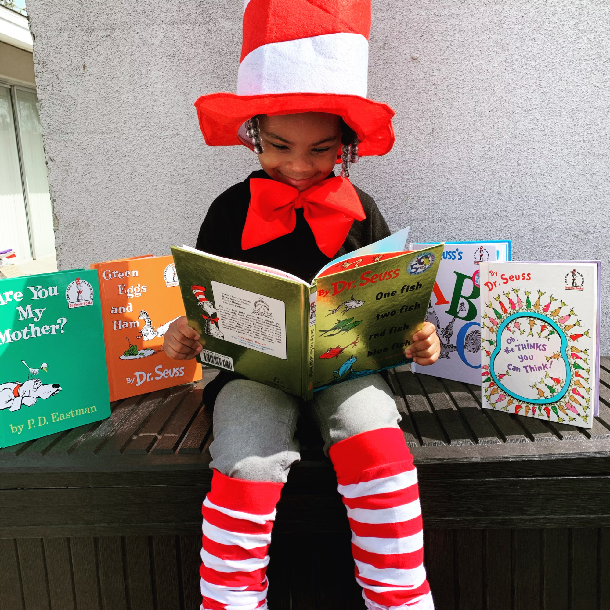 A Black child in a Dr. Seuss costume holds an open book