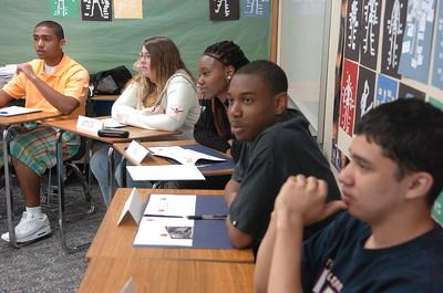 Adolescent students of diverse backgrounds sit at desks in a classroom.