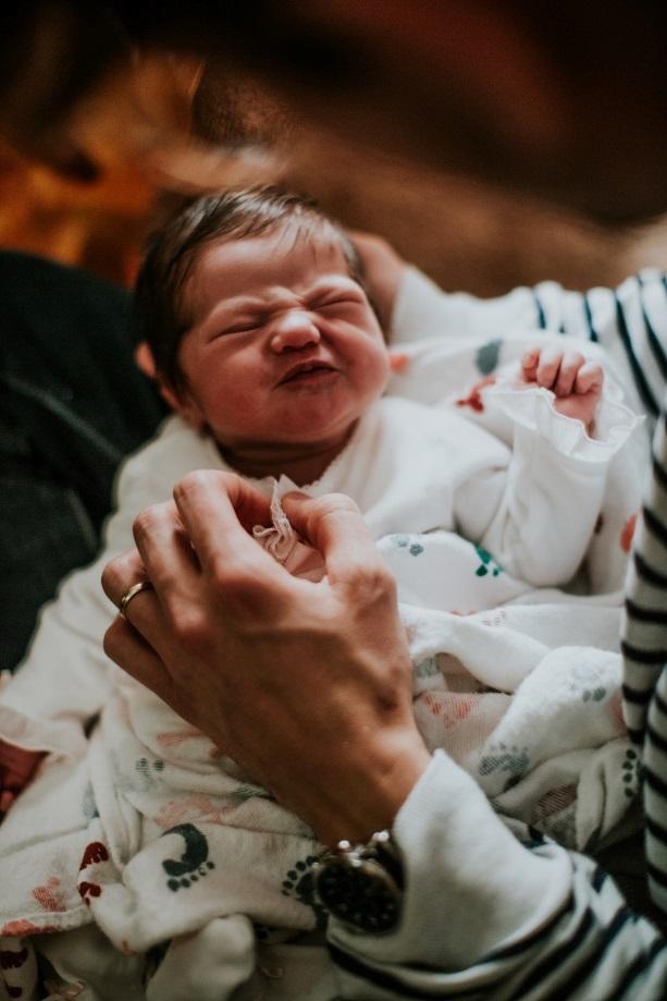 Angry facial expression on baby being held by adult