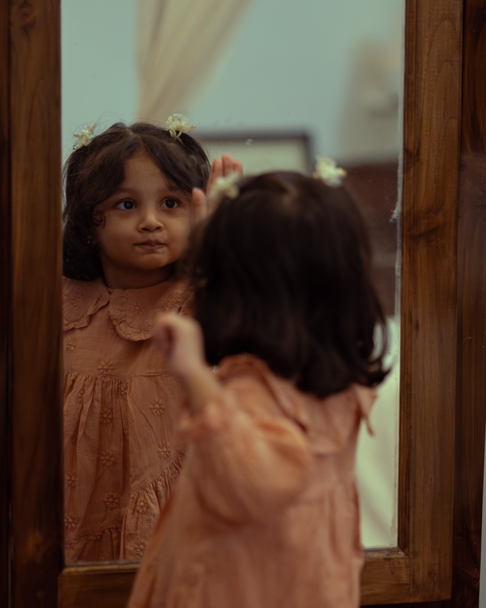 An East Indian child holds their hand up to a mirror