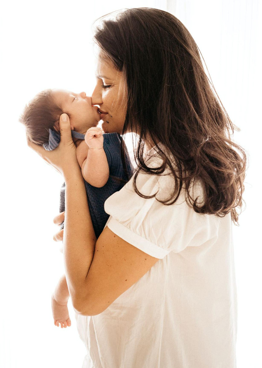 A mother who appears to be oh hispanic heritage holds a newborn baby.