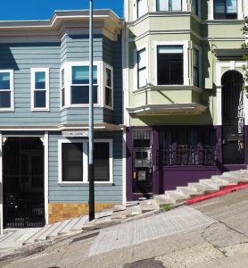 two houses built on a street that slopes down to the left