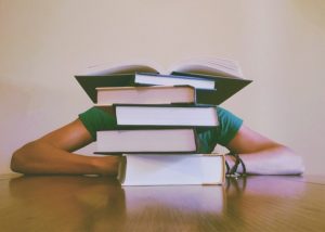 Person hiding behind a pile of books