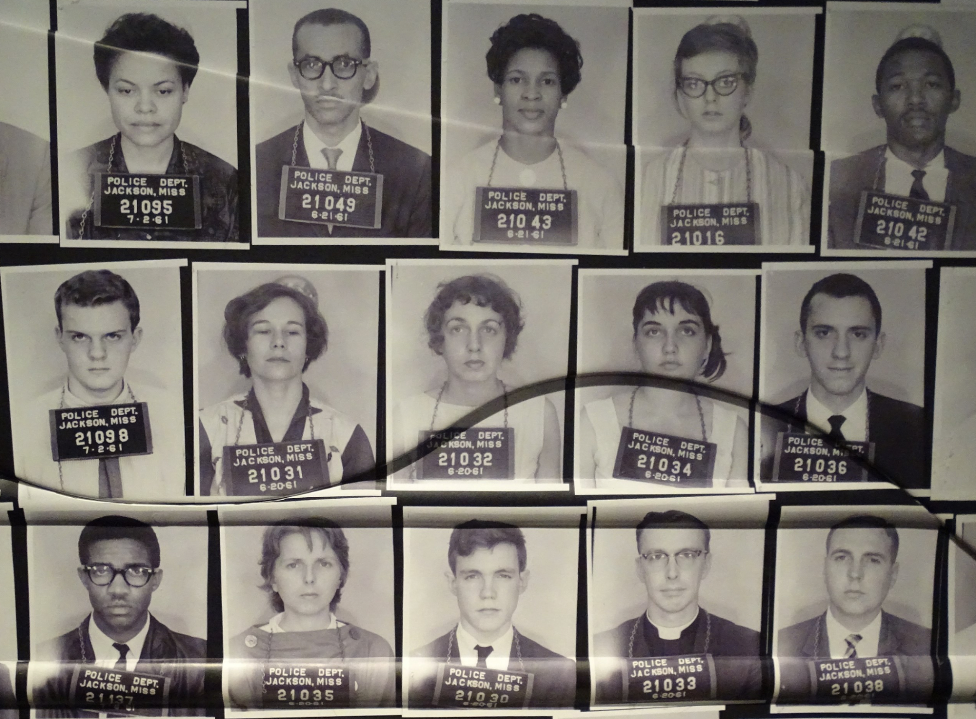 Multiple black and white mugshots of some of the Freedom Riders who are all wearing signs around their necks with the police department's information.