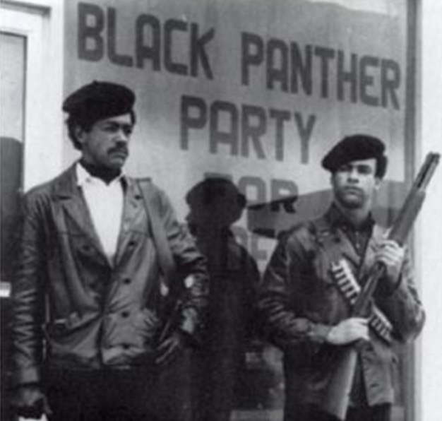 Black and white photo of Black Panther Party founders Bobby Seale and Huey P. Newton standing in the street, armed with a Colt .45 and a shotgun