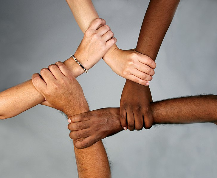 People with different skin tones interlock arms in a star shape
