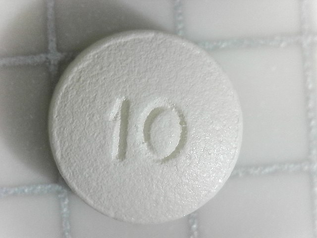 A small white pill - oxycodone - on a counter with the number 10 stamped into it