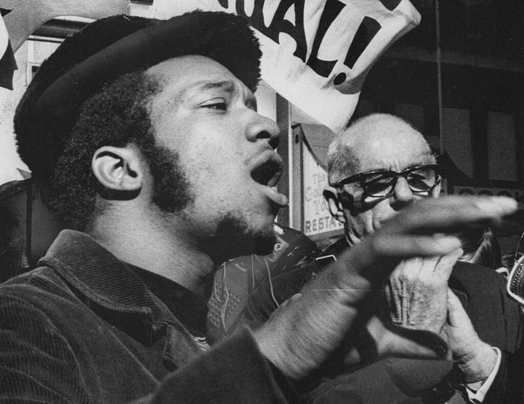 Black and white image of Fred Hampton speaking passionately at a rally