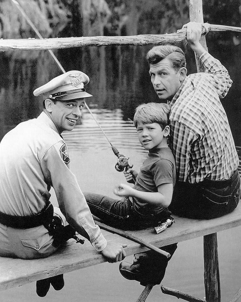 Black and white image of Sheriff Andy Griffith, his son Opie, and Deputy Barney Fife sitting on a dock fishing from the TV show, The Andy Griffith Show
