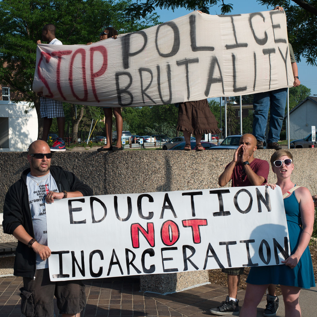 Protest against police brutality in Uptown, banners reading 'Stop Police Brutality' and 'Education Not Incarceration'.