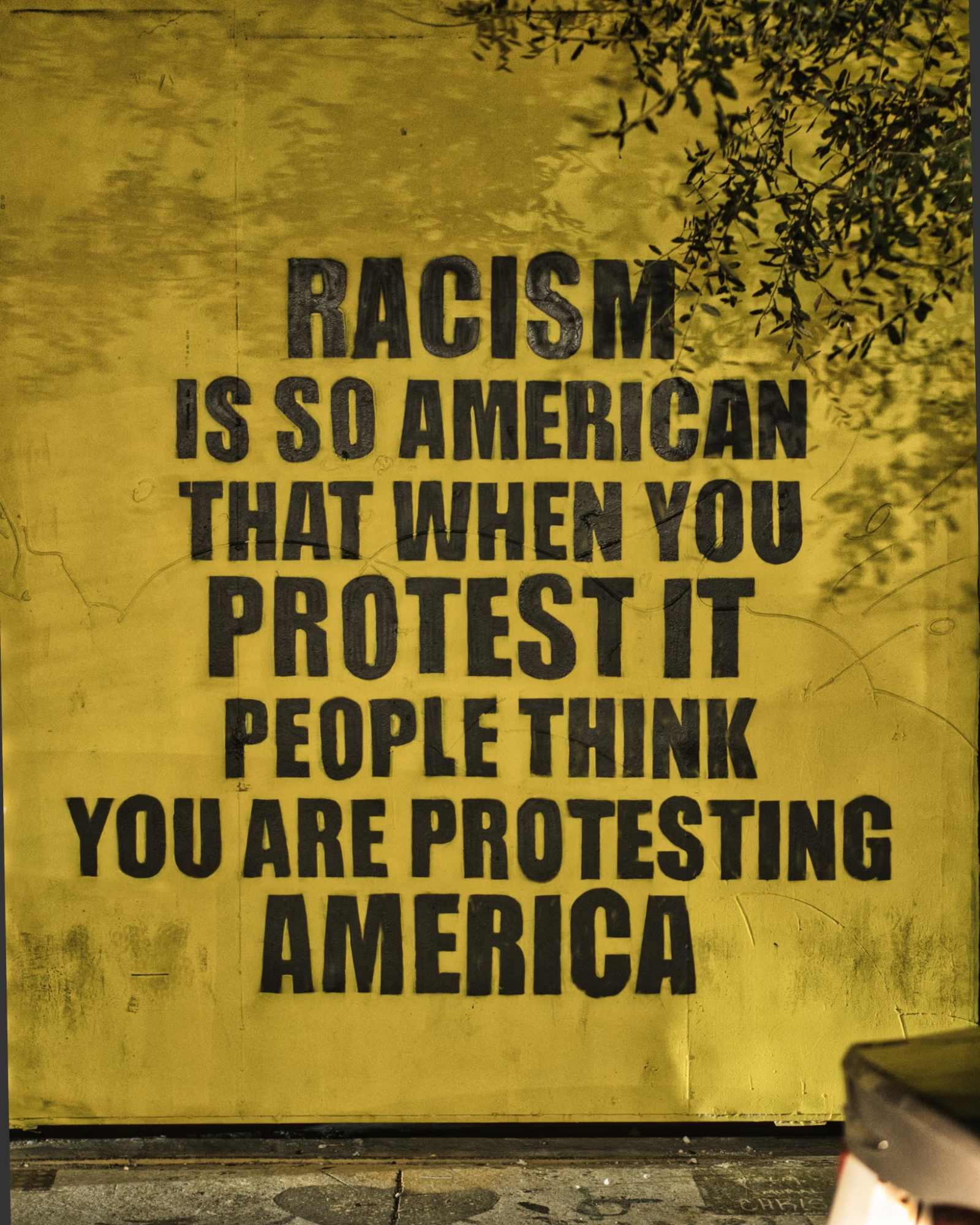 A wall with the phrase "racism is so American that when you protest it people think you are protesting America" painted on it.