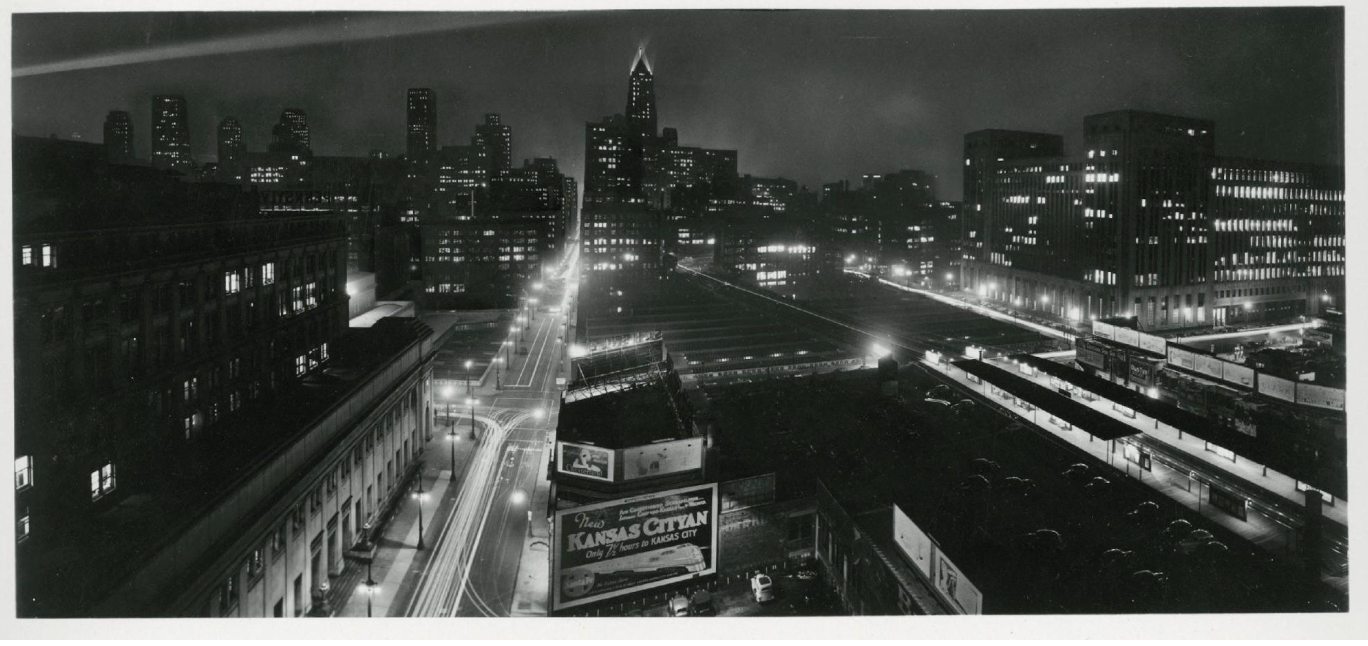 Black and white image of the city of Chicago in the 1930s at night with tall buildings and lights