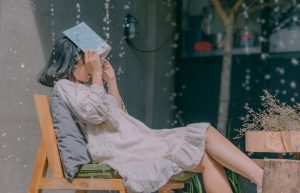 girl sitting on a bench in the rain without an umbrella