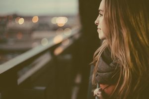 Woman looking out of balcony at city lights