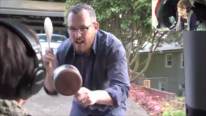 Isaac's brother hitting a pan with a spatula